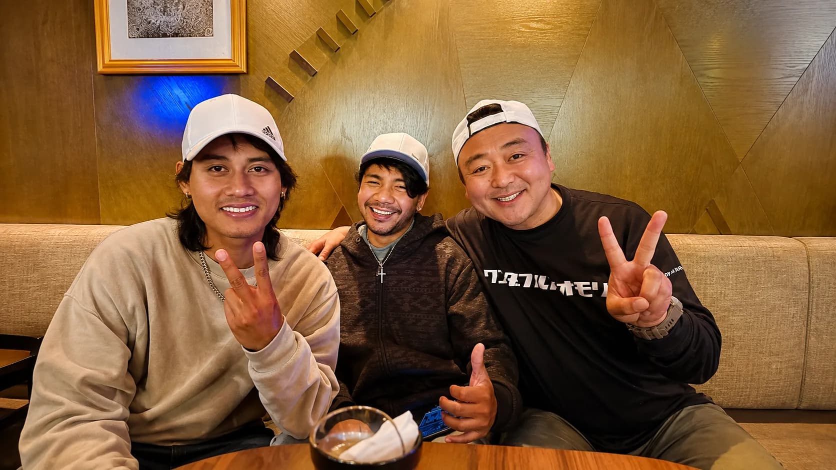 飲食店のテーブルを囲んで話す八戸ペイントの社員3名