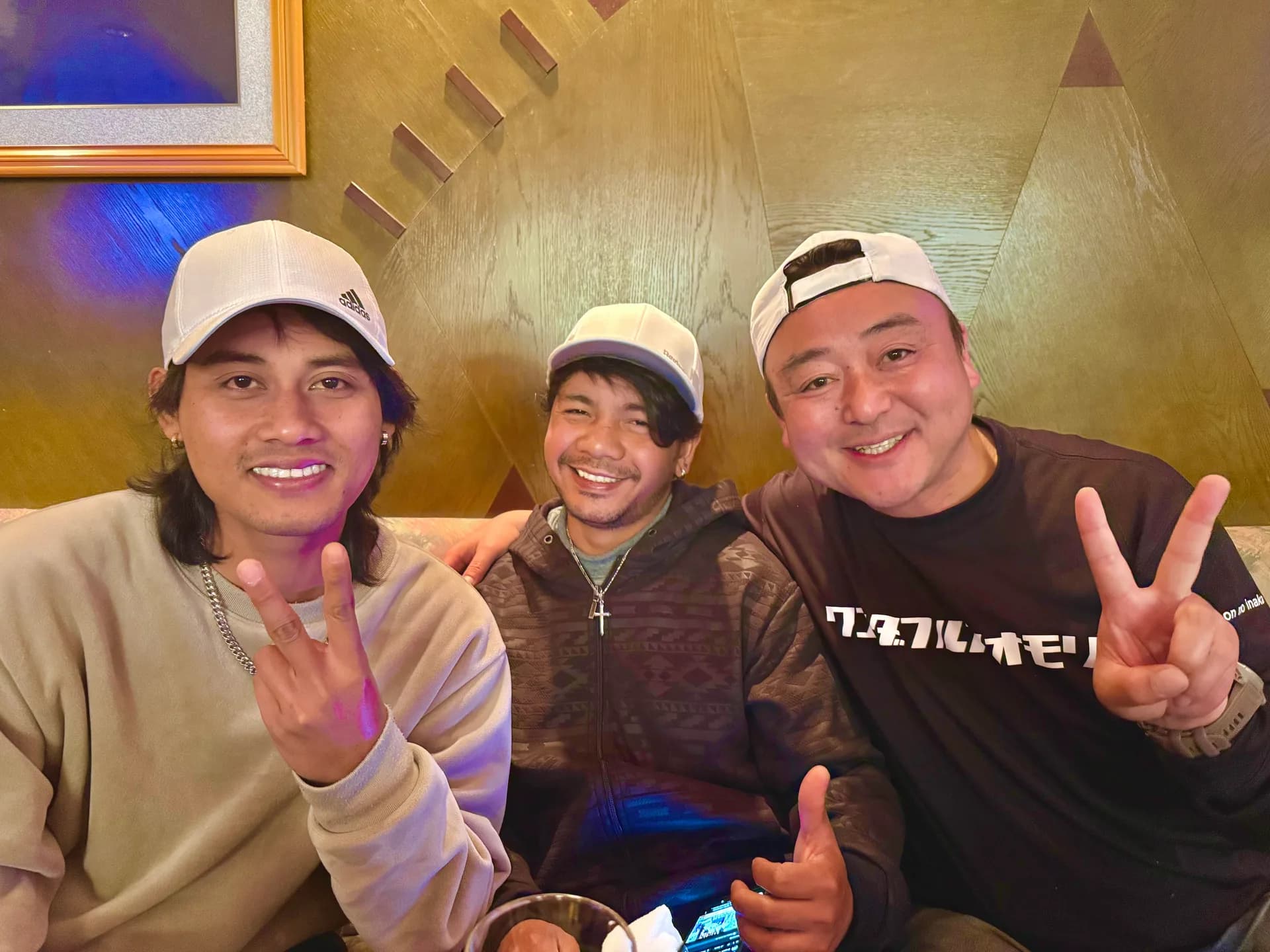 店内のソファ席に並び、笑顔でピースサインをする3人の社員