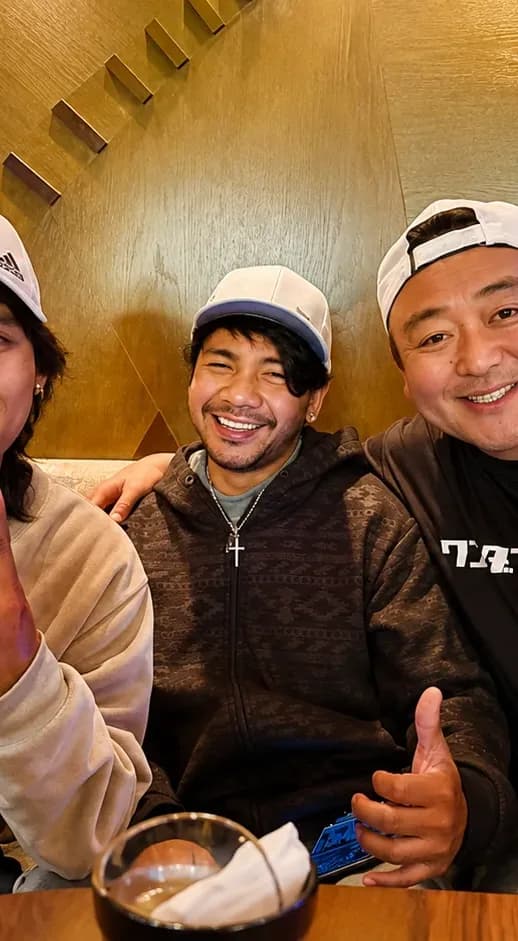 飲食店のテーブルを囲んで笑う八戸ペイントの社員たち