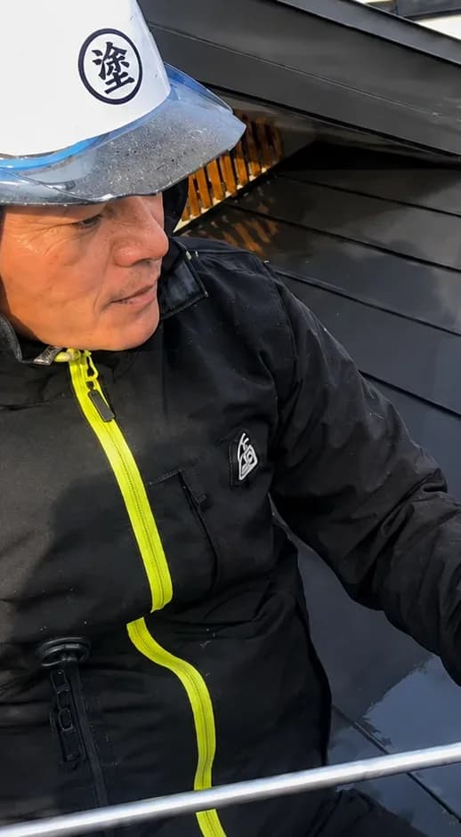 屋根をローラーで塗装する職人