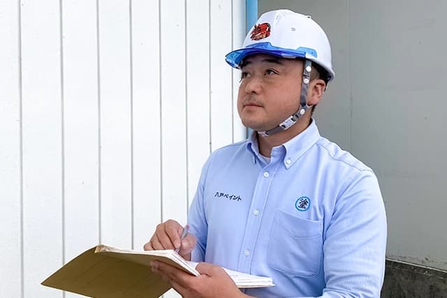 現場でメモを取りながら状況を確認する八戸ペイントの社員