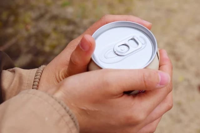 屋外で缶飲料のプルタブを開ける手元