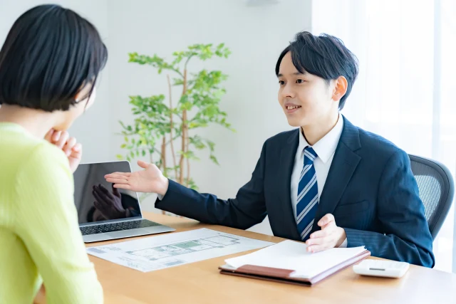 オフィスで図面を広げ、お客様に説明する営業スタッフ
